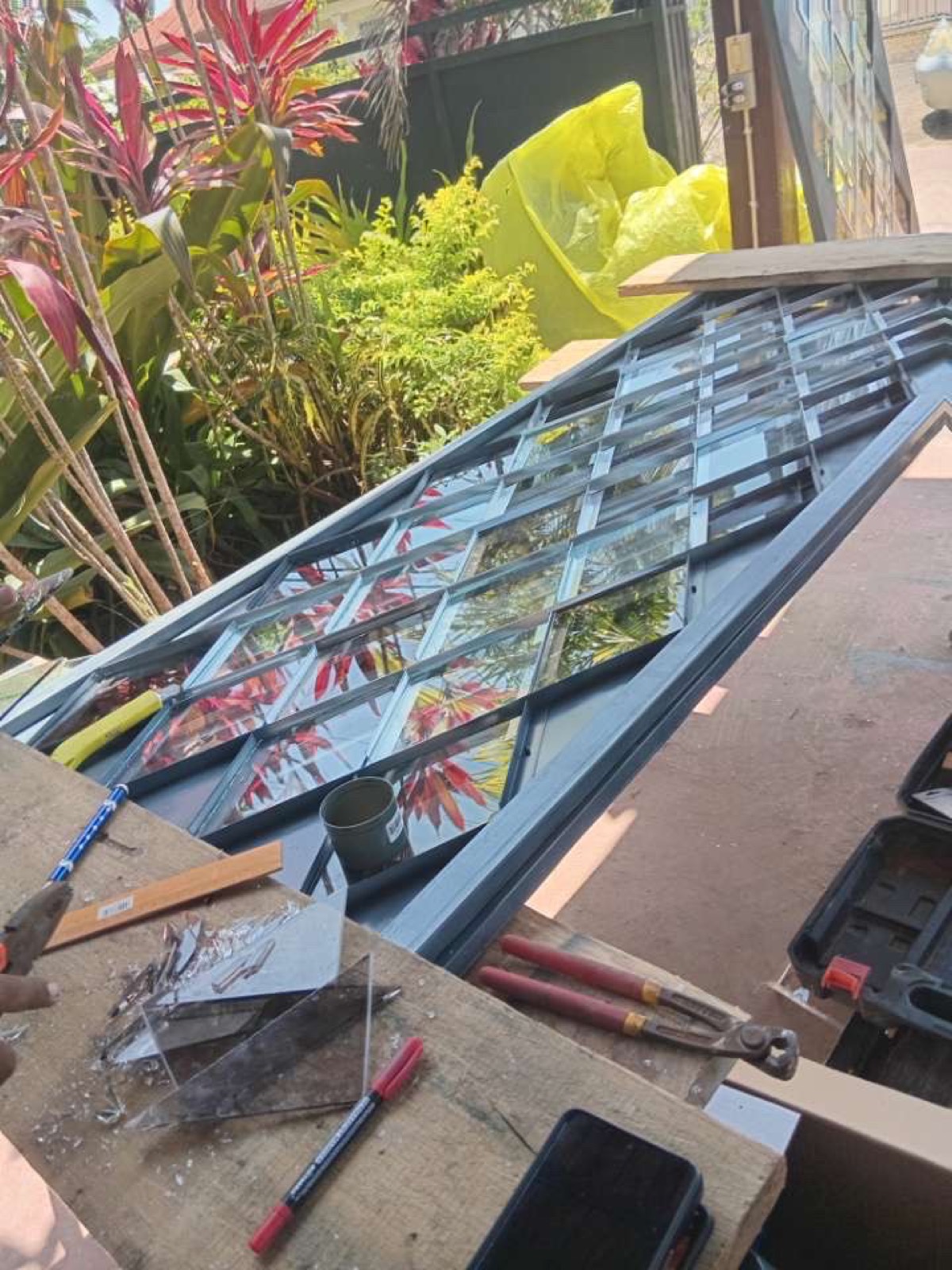 Stalen deur- en raamkozijnen met glas, uitgelegd in de tuin voor montage.